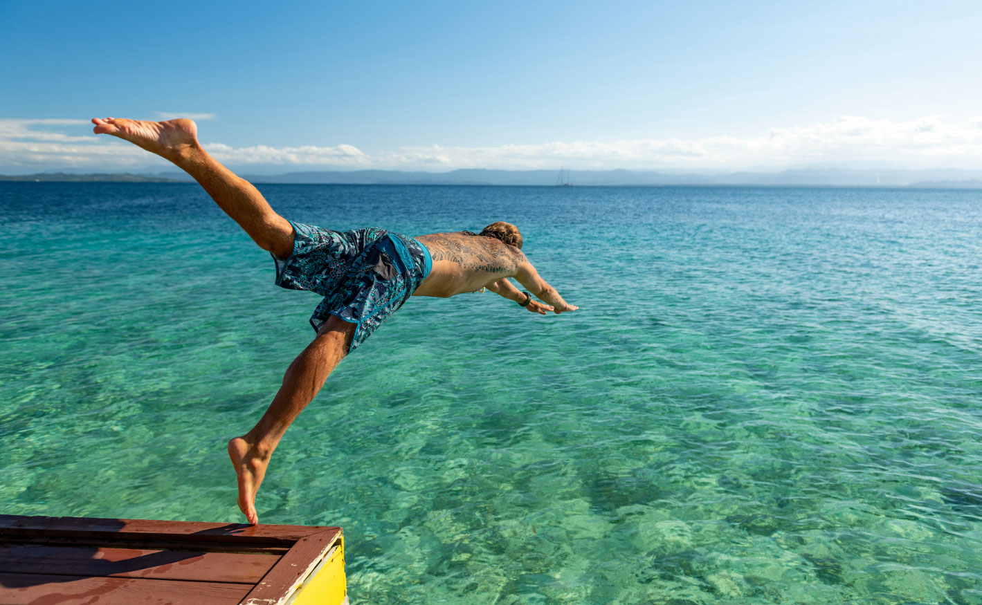 Homem pula na água de um pequeno cais, Ilha Colón, Bocas del Toro.